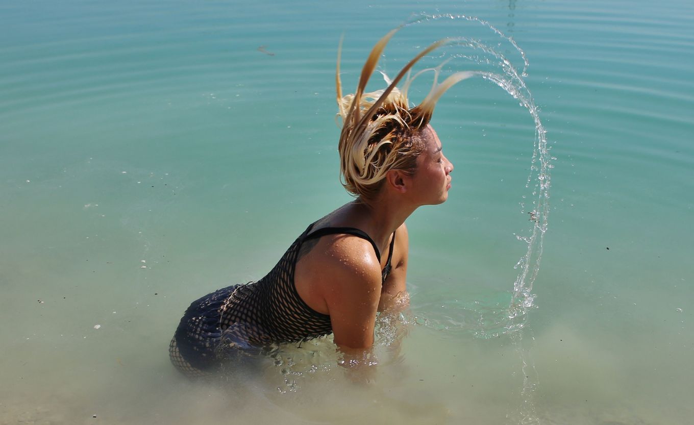 Блонда с татуировкой крыльев на спине, изгибается в разных позах на пляже